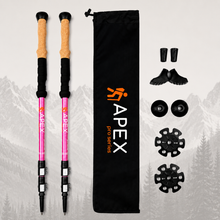 Load image into Gallery viewer, A pair of pink and black Apex Pro Series hiking poles with cork grips, shown alongside a black drawstring bag, toe pads, heel pads, and rubber tips on a light gray background with a faint mountain and forest silhouette.