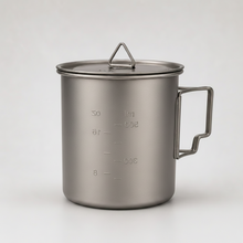 Load image into Gallery viewer, APEX titanium camping 750ml mug with a lid, featuring a side foldable handle, embossed measurement markings, and a small triangular handle loop on top, shown against a neutral light gray background.