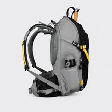 Load image into Gallery viewer, APEX  black X34 hiking backpack with yellow accents, shown from a three-quarters angle on a light gray background. A hiking pole is tucked into the top compartment, and a water bottle is visible in the side pocket.
