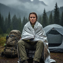 Load image into Gallery viewer, Front view of person wrapped in a silver mylar blanket on a white background, APEX survival blanket, emergency
